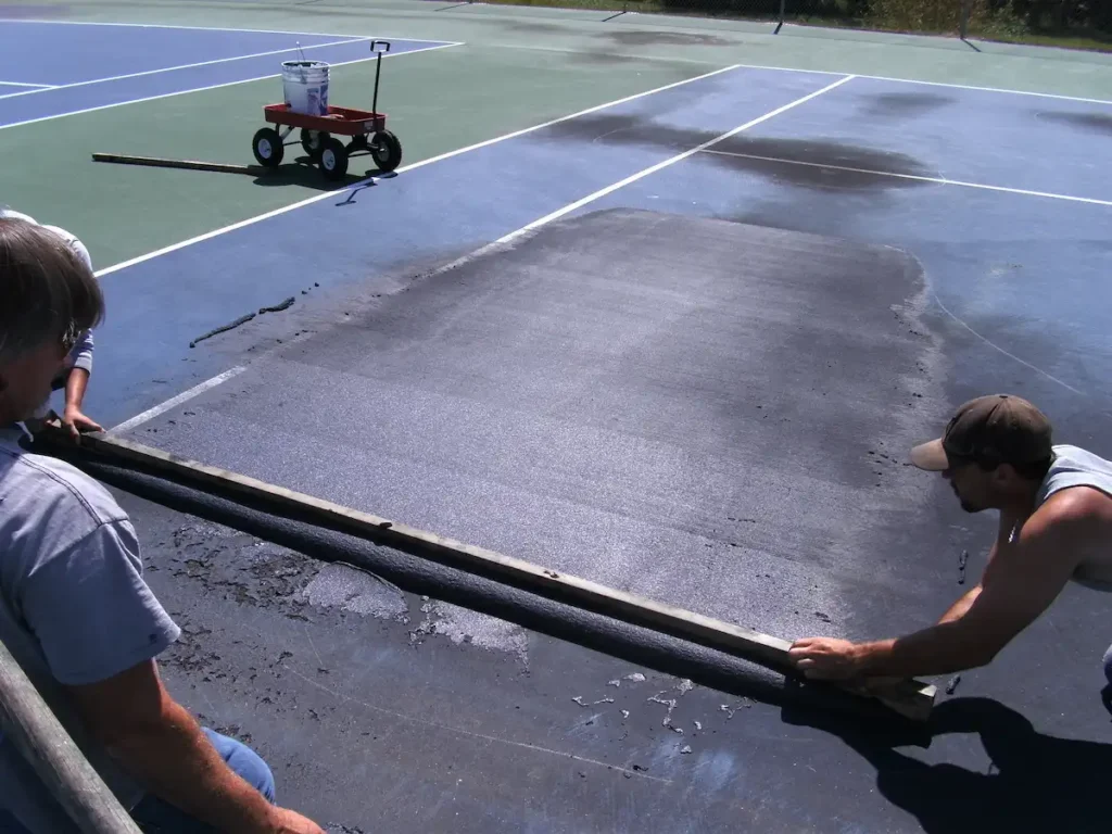 crew performing tennis court crack repair before resurfacing installation